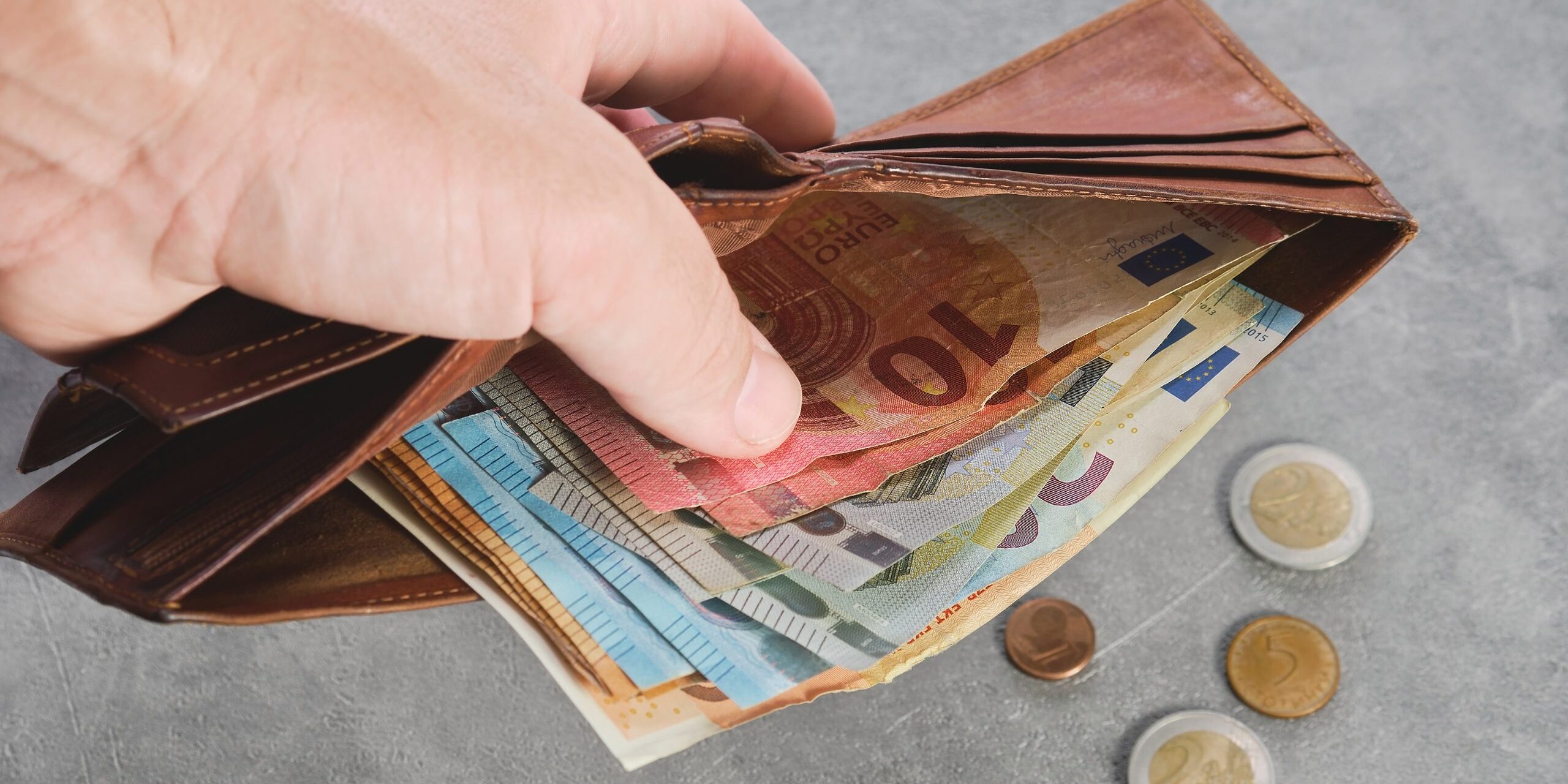 Senior man holds a wallet with euro banknotes in his hand, euro banknotes in the wallet. Wallet with money in a man’s hand, background idea of paying taxes, buying or paying for services