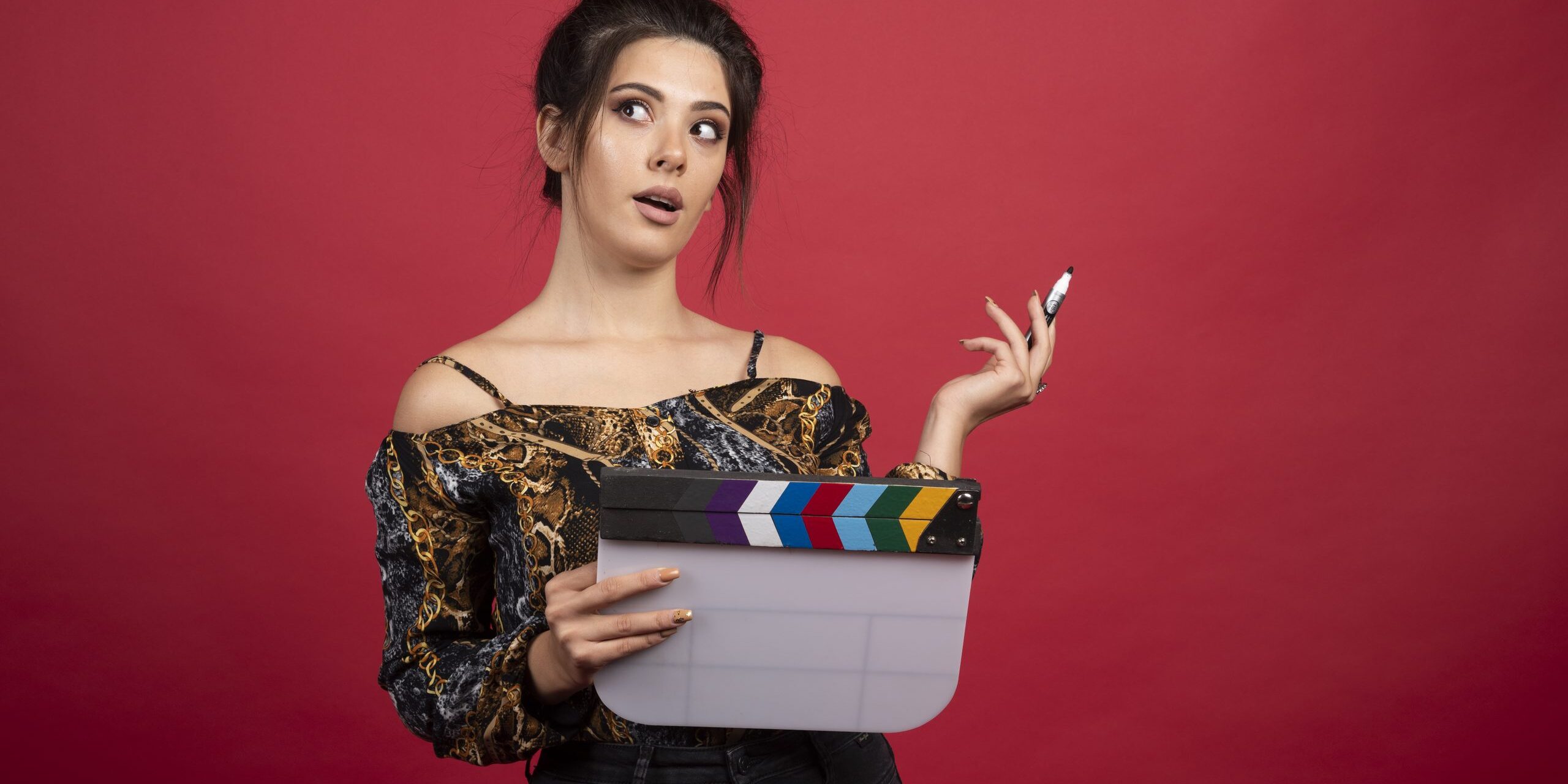 Girl with a clapper board looks thoughtful and confused